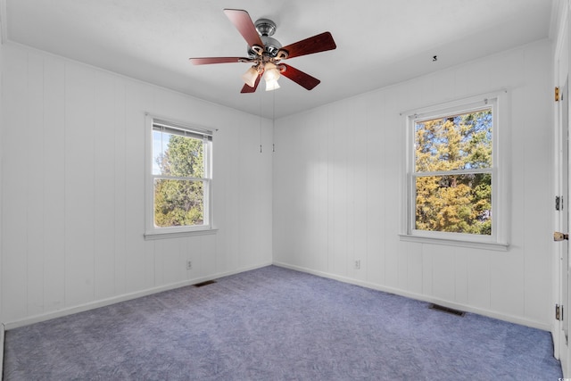 carpeted empty room with baseboards, visible vents, and a ceiling fan