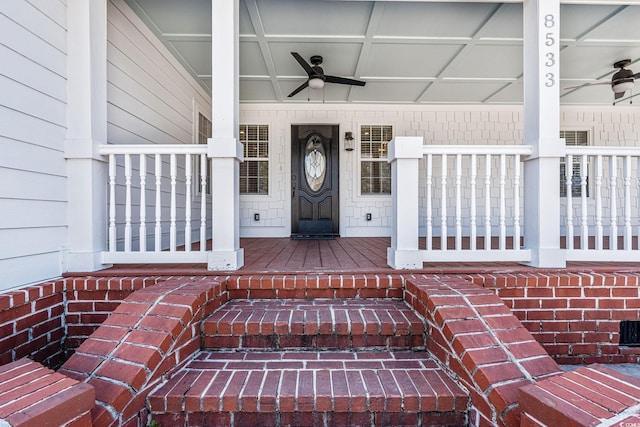 property entrance featuring a ceiling fan, covered porch, and brick siding