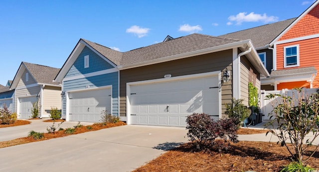 view of side of property with a garage, concrete driveway, and roof with shingles