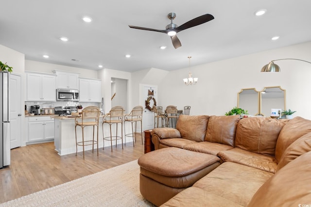 living room featuring light wood-style floors, ceiling fan with notable chandelier, and recessed lighting