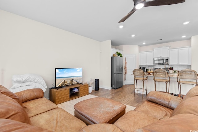 living area featuring light wood-type flooring, ceiling fan, and recessed lighting