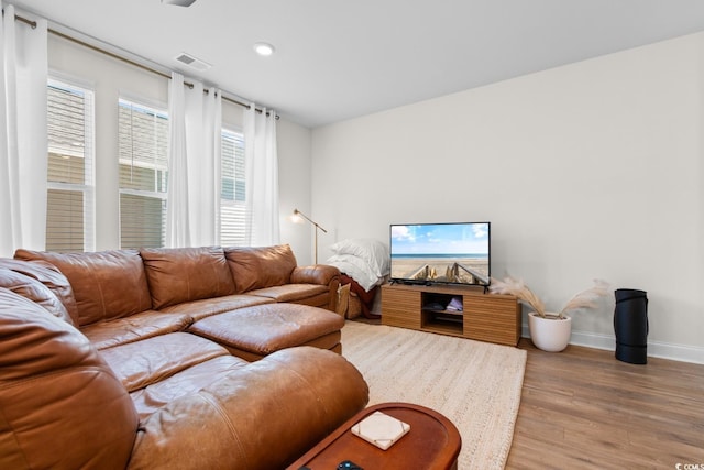 living room with light wood-style floors, baseboards, and visible vents