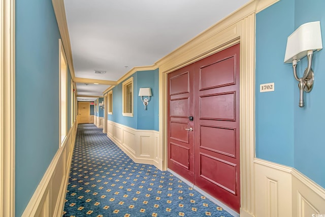 corridor featuring wainscoting, dark carpet, and visible vents