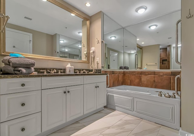 bathroom featuring marble finish floor, visible vents, a bath, and vanity