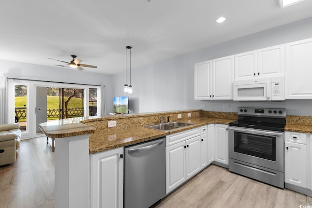 kitchen with a peninsula, white cabinetry, stainless steel appliances, and a sink