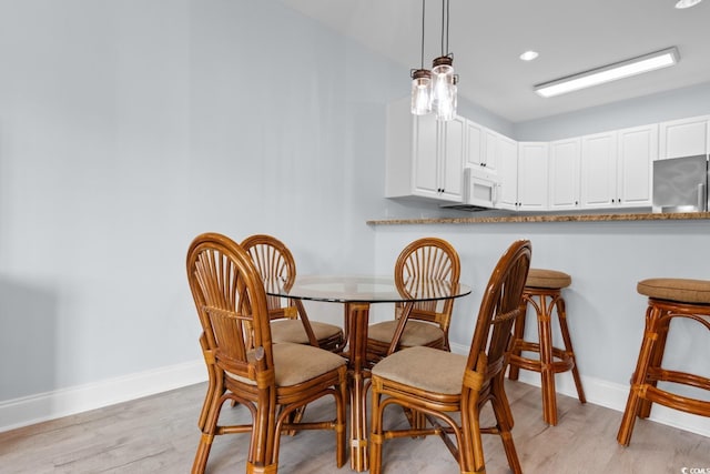 dining space with light wood-type flooring and baseboards