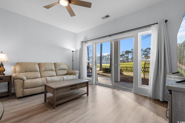 living room featuring light wood finished floors, visible vents, and a ceiling fan