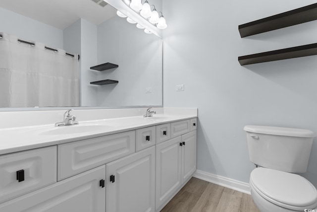 full bathroom featuring double vanity, a sink, toilet, and wood finished floors