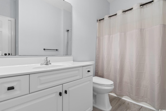 bathroom with toilet, a shower with curtain, wood finished floors, and vanity