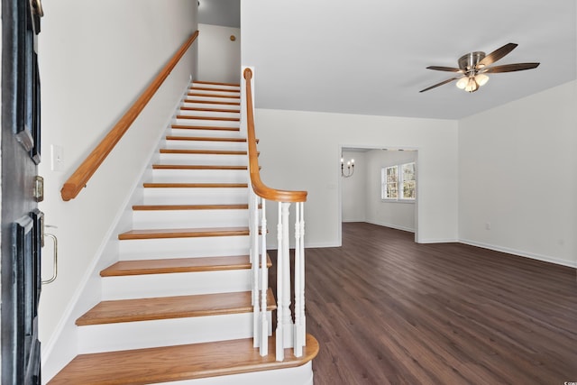 stairs featuring baseboards, wood finished floors, and ceiling fan with notable chandelier