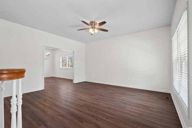 unfurnished living room featuring dark wood-type flooring, baseboards, and ceiling fan with notable chandelier