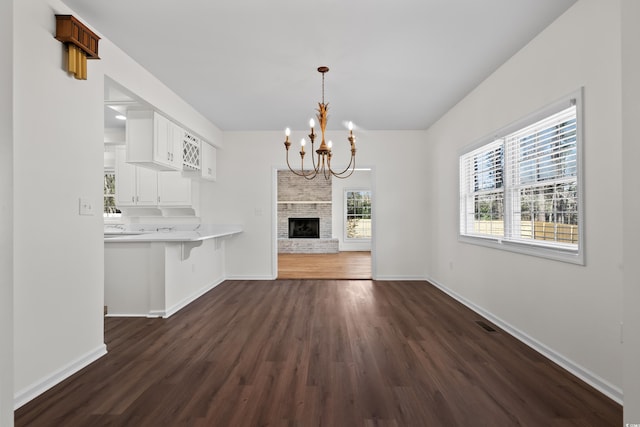 unfurnished dining area featuring dark wood finished floors, baseboards, and a chandelier