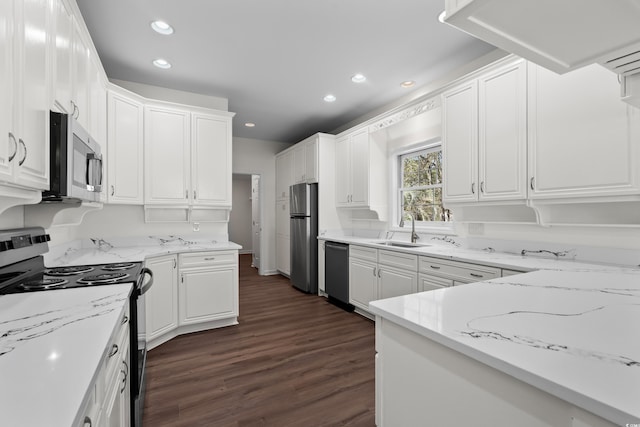 kitchen featuring recessed lighting, dark wood finished floors, stainless steel appliances, a sink, and white cabinetry