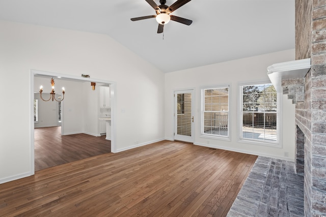 unfurnished room with vaulted ceiling, hardwood / wood-style floors, baseboards, and ceiling fan with notable chandelier