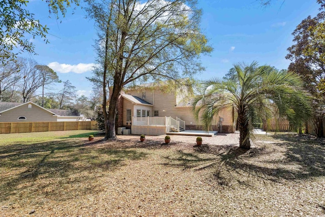 rear view of house with a deck, a lawn, a patio area, and fence