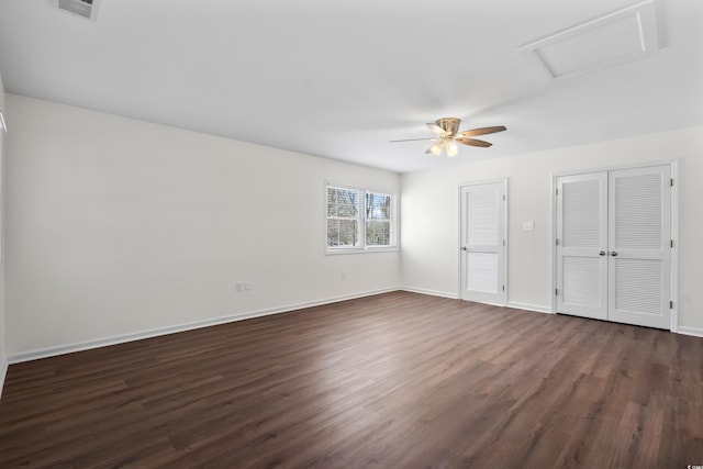 unfurnished bedroom with attic access, two closets, ceiling fan, baseboards, and dark wood-style floors