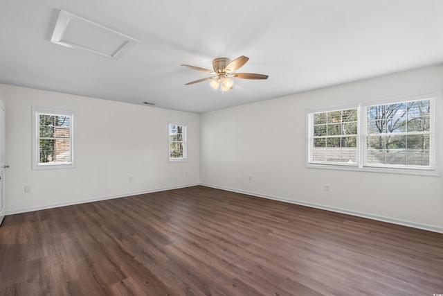 unfurnished room with dark wood-style floors, ceiling fan, attic access, and baseboards