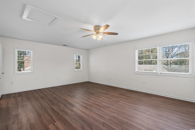 empty room with attic access, baseboards, a ceiling fan, and dark wood-style floors