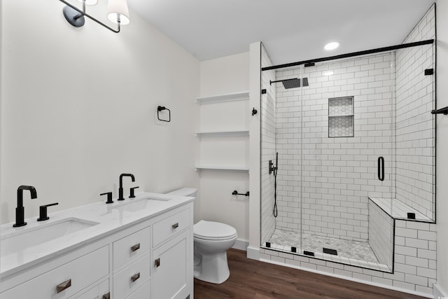 full bathroom featuring wood finished floors, a sink, toilet, and a shower stall