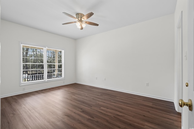 unfurnished room featuring dark wood-style floors, ceiling fan, and baseboards