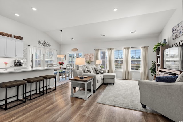 living area with lofted ceiling, wood finished floors, visible vents, and recessed lighting