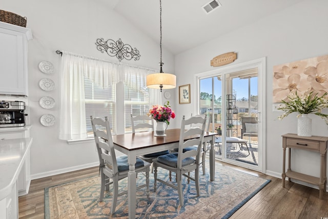 dining area with lofted ceiling, wood finished floors, visible vents, and baseboards