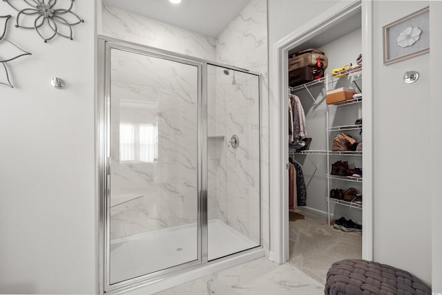 full bath with marble finish floor, a marble finish shower, and a walk in closet