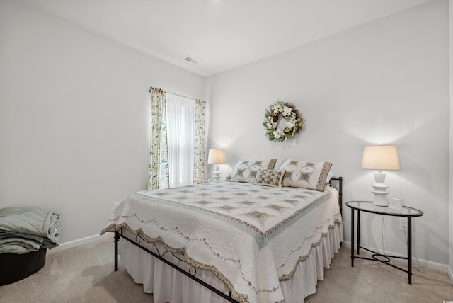 bedroom with baseboards, visible vents, and light colored carpet