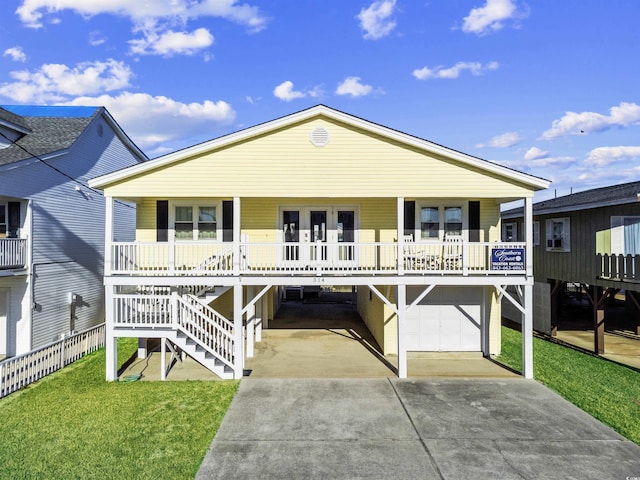 coastal inspired home featuring a porch, concrete driveway, a front lawn, and stairs