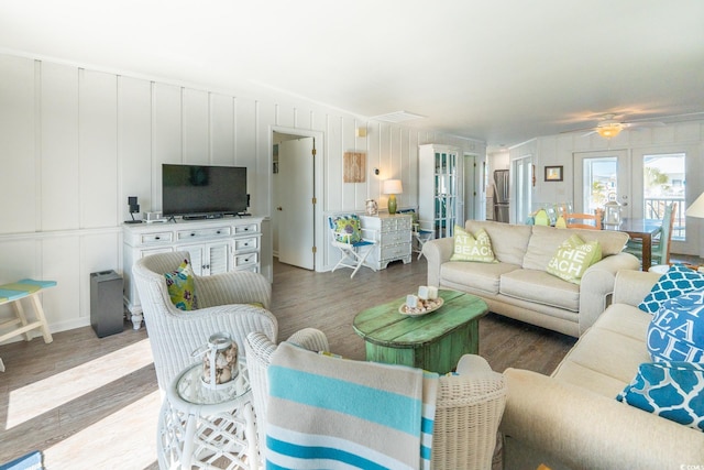 living area with lofted ceiling, french doors, a decorative wall, and light wood-style flooring