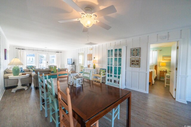 dining space with a ceiling fan, a decorative wall, and wood finished floors