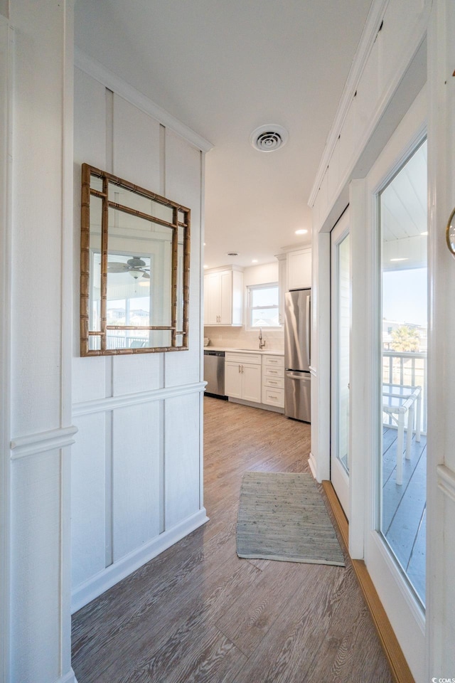 interior space with visible vents, light wood-style flooring, appliances with stainless steel finishes, white cabinetry, and a sink