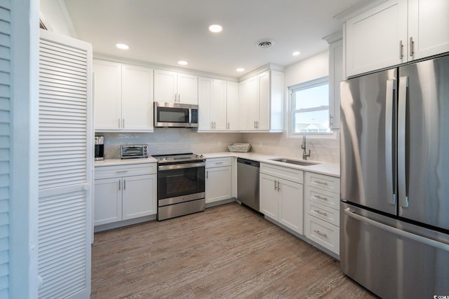 kitchen with light countertops, visible vents, appliances with stainless steel finishes, white cabinets, and a sink