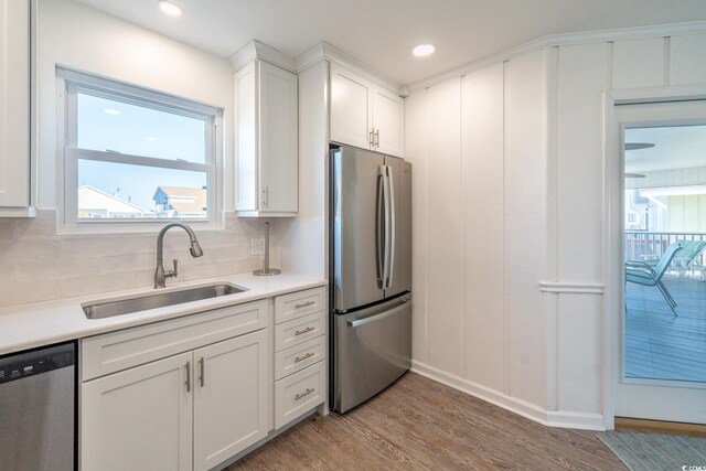 kitchen featuring white cabinets, stainless steel appliances, a sink, and light countertops