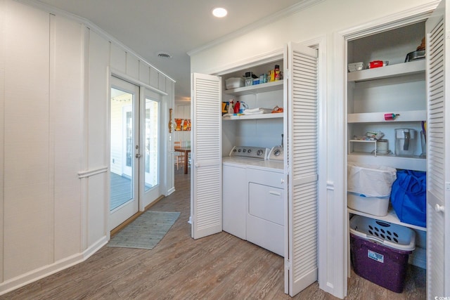 laundry area with laundry area, ornamental molding, wood finished floors, washer and dryer, and french doors