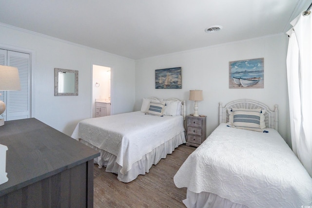 bedroom with wood finished floors, visible vents, and crown molding