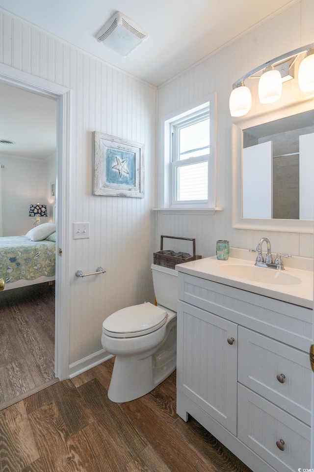 ensuite bathroom with toilet, connected bathroom, visible vents, and wood finished floors