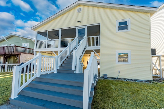 exterior space with a sunroom, ceiling fan, stairway, and a front lawn