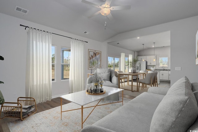 living room featuring lofted ceiling, visible vents, and light wood-style floors