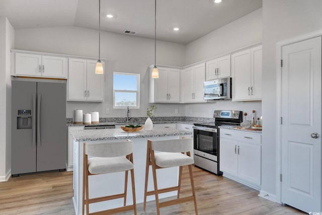 kitchen featuring appliances with stainless steel finishes, a center island, visible vents, and white cabinetry