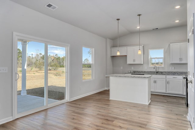 kitchen with light wood-type flooring, a center island, white cabinetry, and a sink