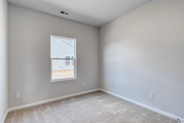 spare room with carpet floors, visible vents, and baseboards