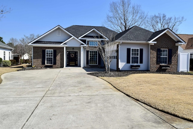 view of front of property featuring brick siding and roof with shingles