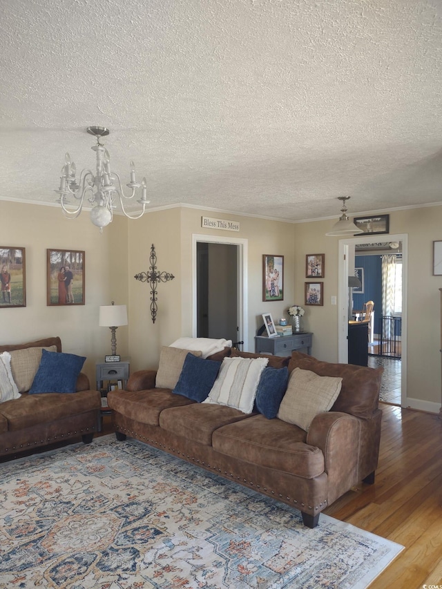 living room featuring light wood-type flooring, a notable chandelier, crown molding, and a textured ceiling