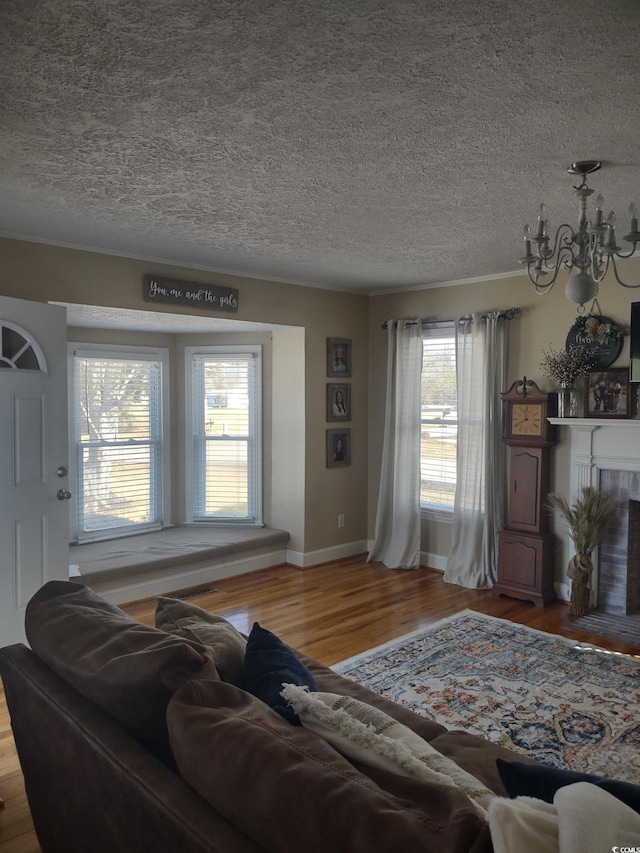 living area featuring a textured ceiling, a fireplace, wood finished floors, and baseboards