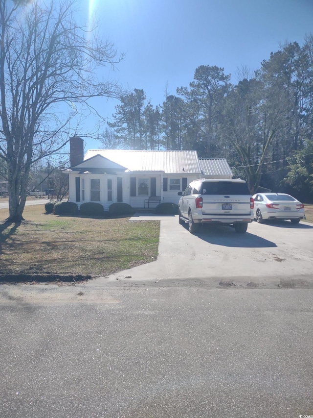 view of front facade with a front yard, driveway, and a chimney