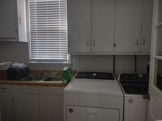 clothes washing area featuring cabinet space, a sink, and washer and clothes dryer