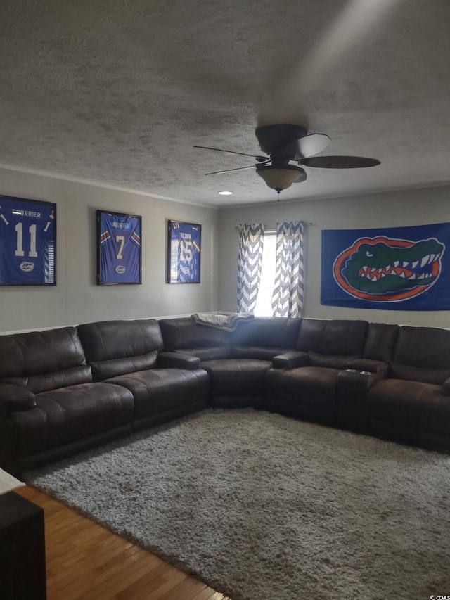 living room with a textured ceiling, a ceiling fan, and wood finished floors