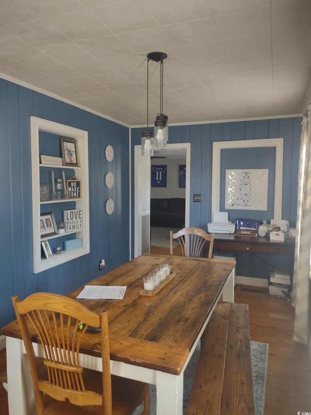 dining space with crown molding and wood finished floors