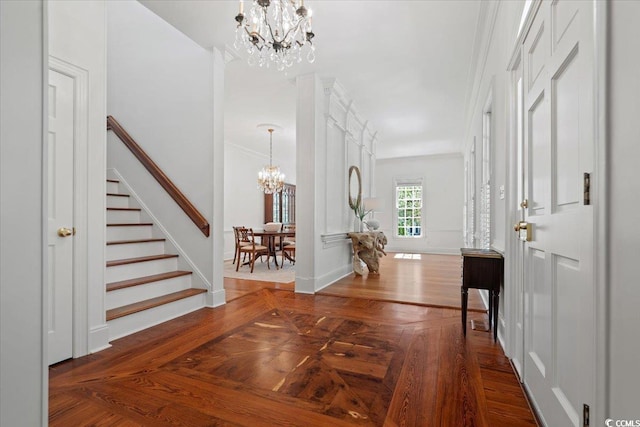 foyer with baseboards, stairway, parquet floors, crown molding, and a notable chandelier